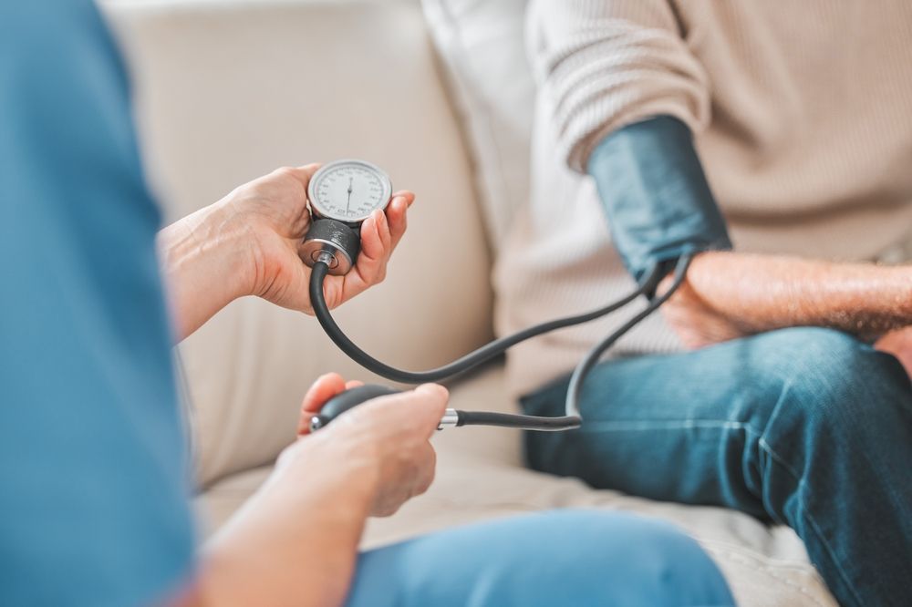 Nurse taking a patient's blood pressure with a manual sphygmomanometer.